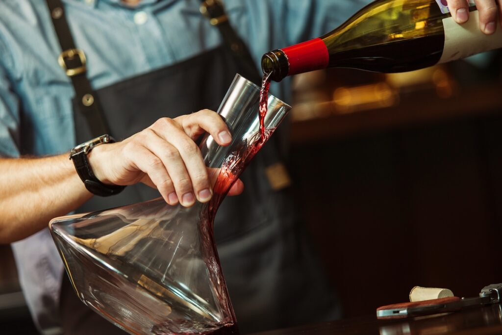 Sommelier häller upp vin i en karaff